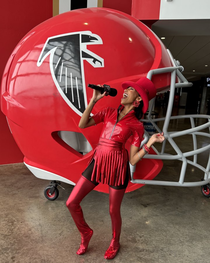 Chelsea singing into the mic beside a giant Falcons helmet