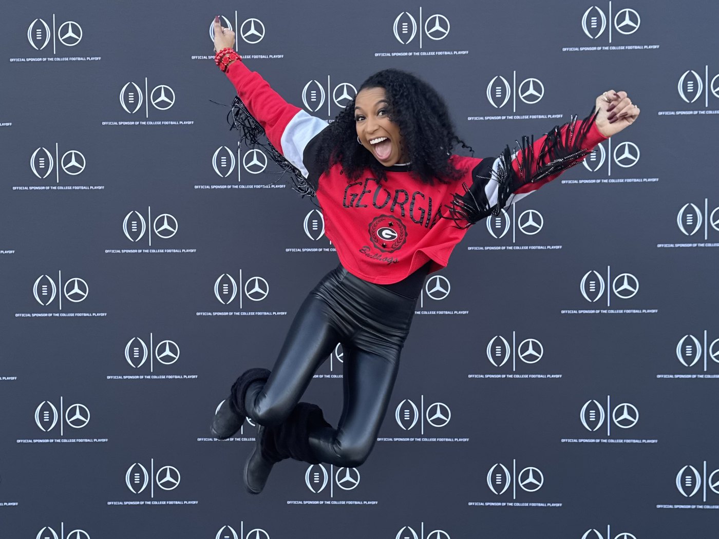 Chelsea jumping for joy in front of the Mercedes-Benz backdrop at the game day watch party